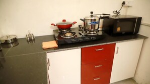 Una cocina compacta con estufa a gas, microondas y un armario rojo y blanco.