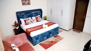 Un dormitorio con una cama, un sofá rojo, una puerta de madera y armarios blancos.
