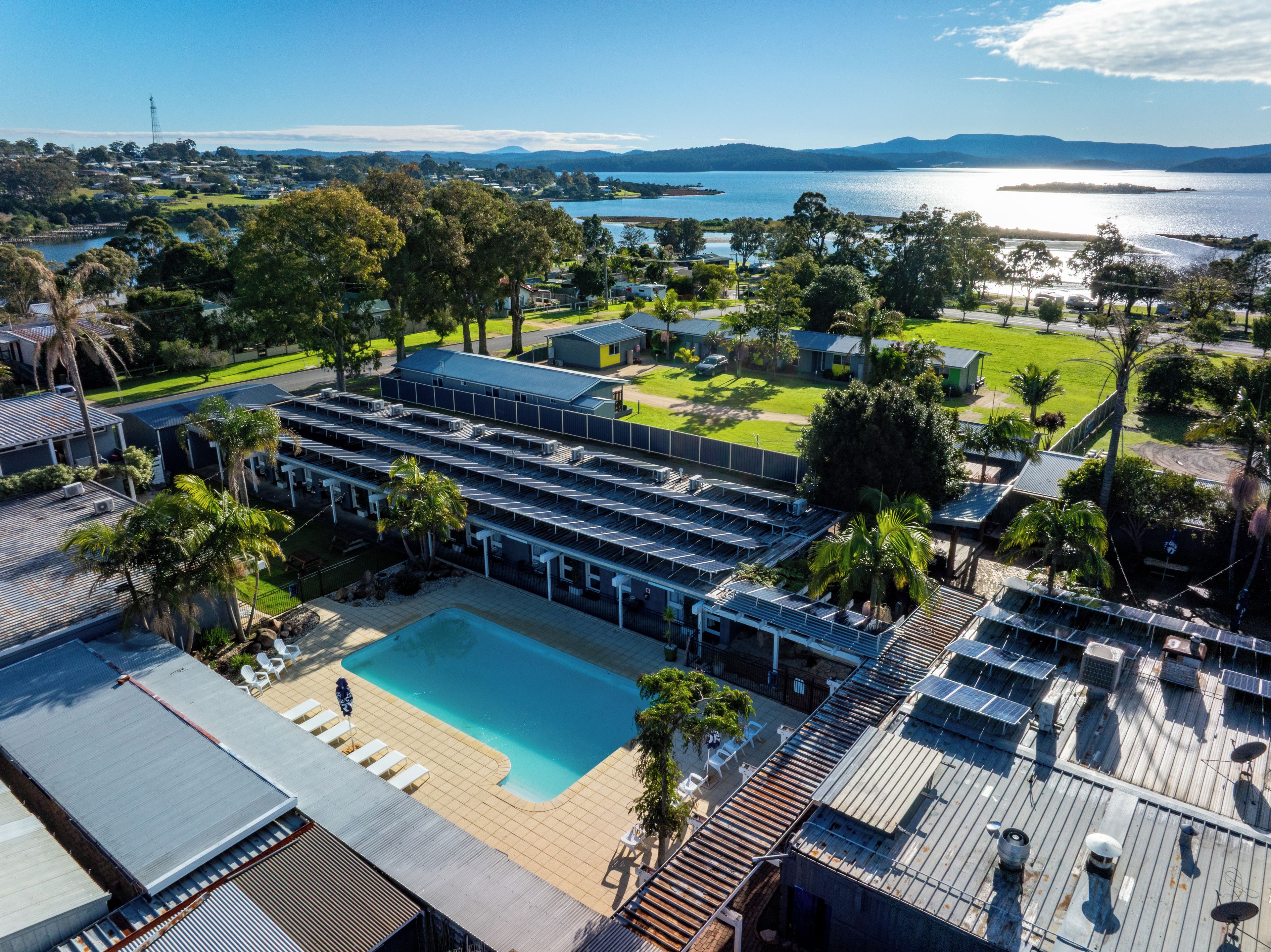 A resort with a swimming pool, solar panels, and a view of the lake.