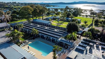 A resort with a swimming pool, solar panels, and a view of the lake.