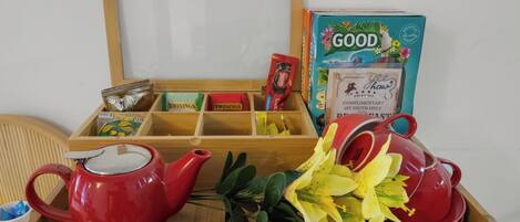 Una bandeja de madera con una tetera roja, una taza roja, una caja de Good Oats y una caja de té Twinings.