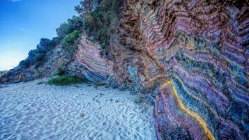 A beach with white sand and colorful rock formations.