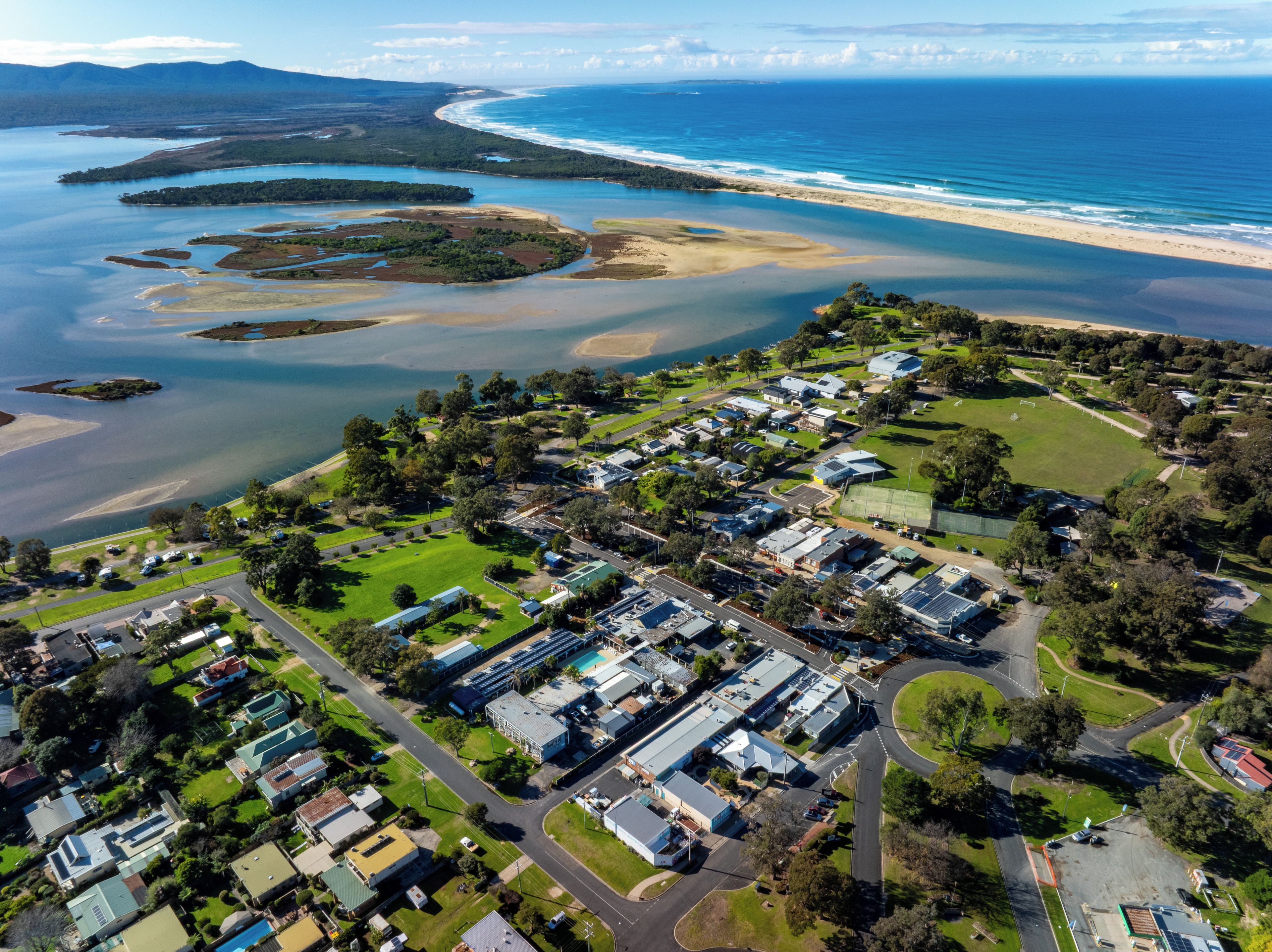 An aerial view of a coastal residential area with houses, roads, and a beach.