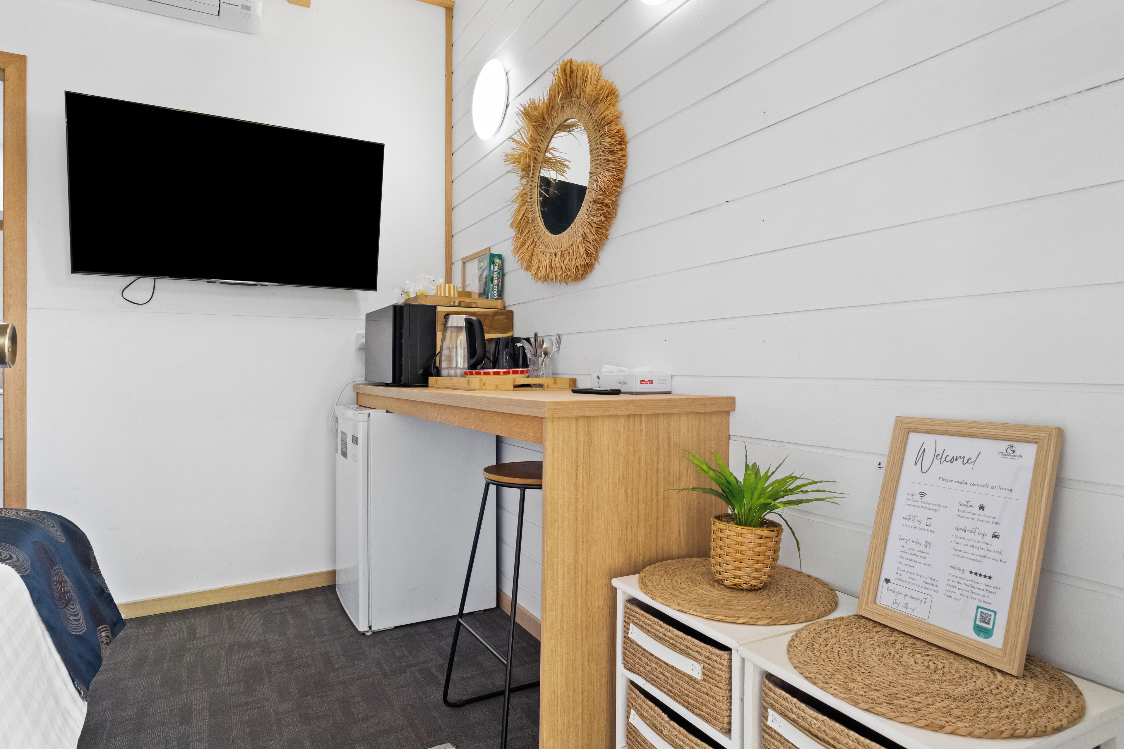 A modern kitchen area with a flat-screen TV, a refrigerator, a coffee machine, and a small bar counter.