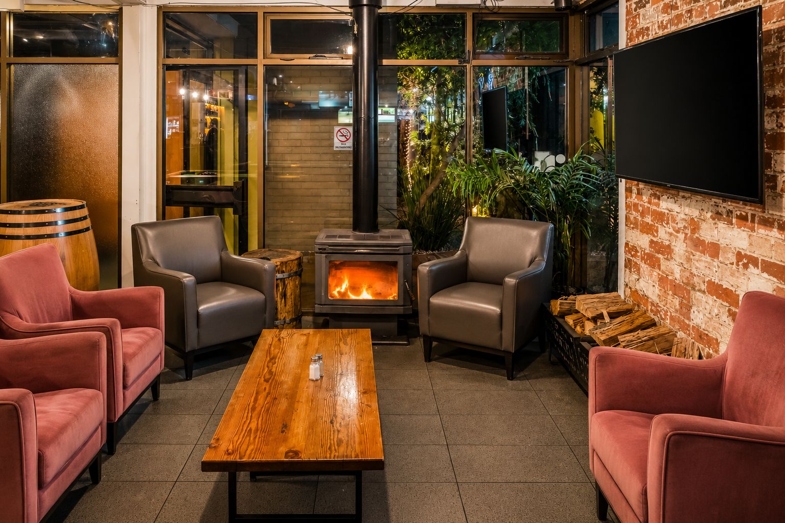 A cozy indoor seating area with a wood-burning stove, leather chairs, and a wooden table.