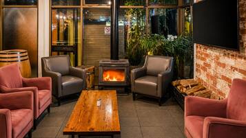 A cozy indoor seating area with a wood-burning stove, leather chairs, and a wooden table.