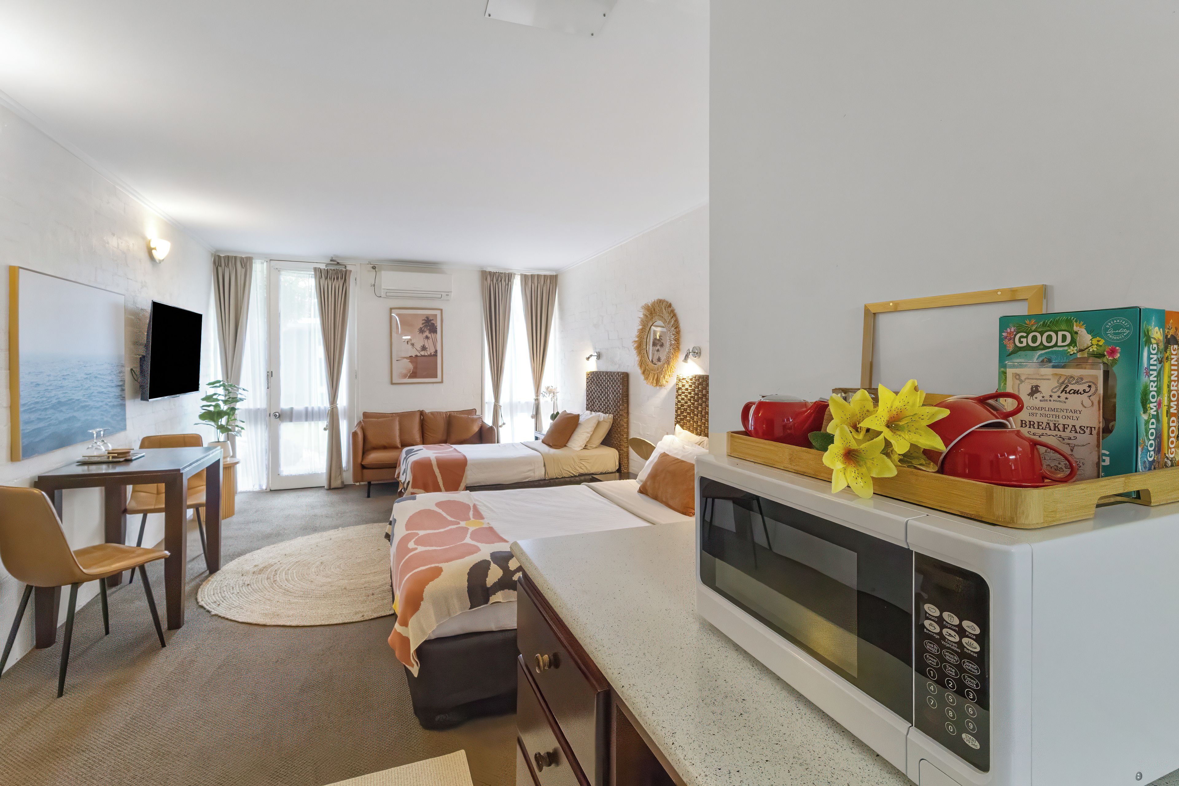 Una cocina moderna con microondas, un comedor con sillas, un sofá y un televisor.
