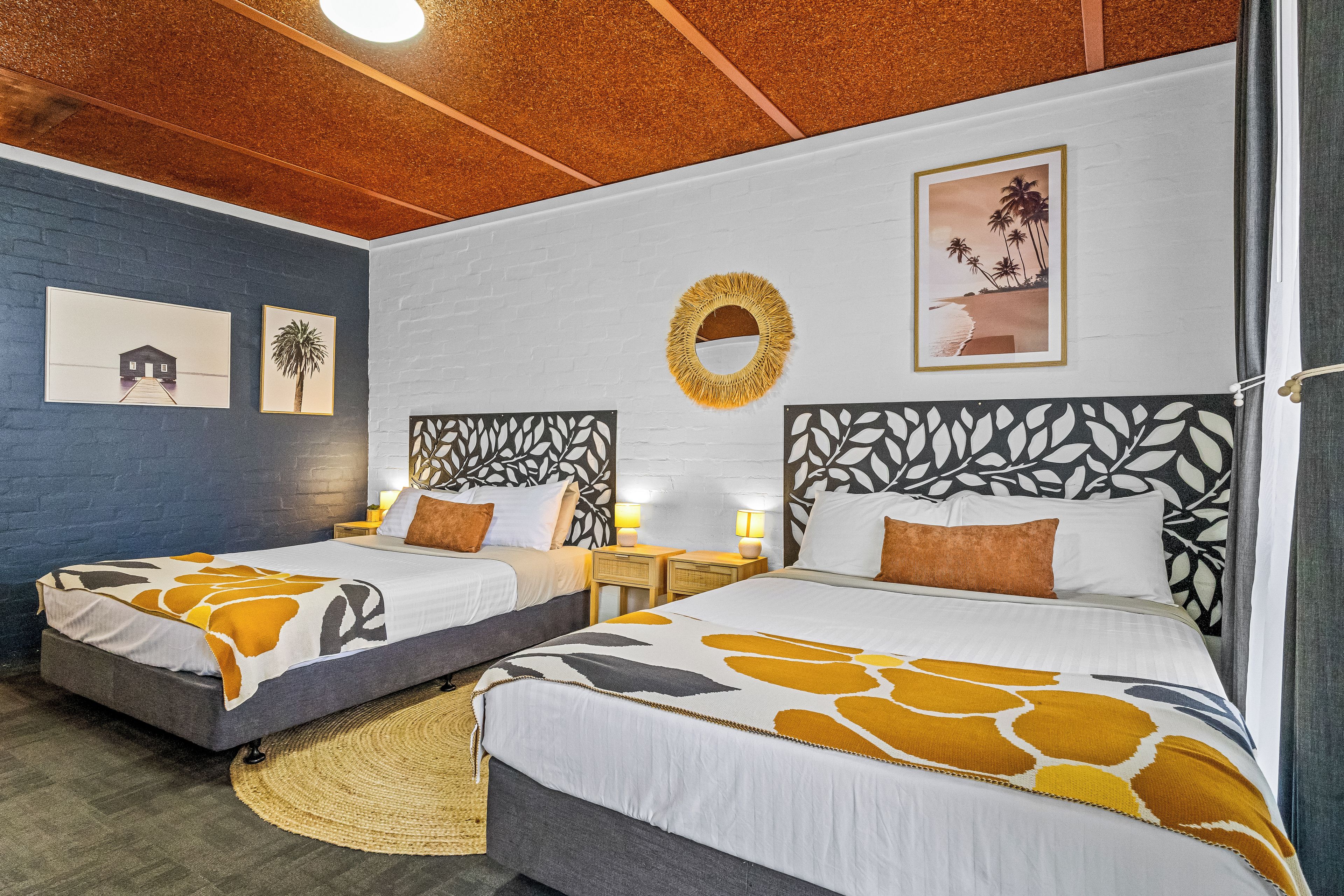Een hotelkamer met twee bedden, een ronde spiegel en kunst aan de muren.
