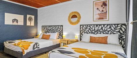 Een hotelkamer met twee bedden, een ronde spiegel en kunst aan de muren.