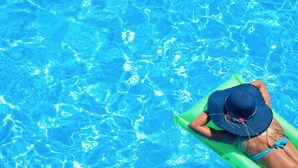 A person relaxing on a green float in a clear blue pool. - Mallacoota Hotel Motel (Mallacoota)