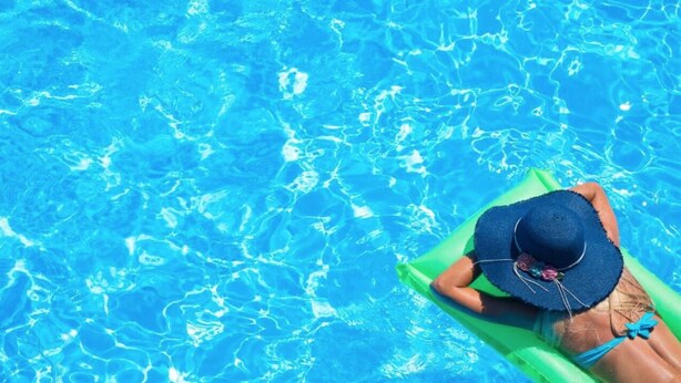 A person relaxing on a green float in a clear blue pool. - Mallacoota Hotel Motel (Mallacoota)