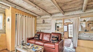 A rustic wooden interior with a leather sofa, a coffee table, and a mirror.