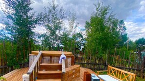 Une terrasse en bois avec un jacuzzi, des marches en bois et un banc.