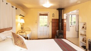 Ein Schlafzimmer mit einem Bett, einem Tisch mit Stühlen, einem Kamin und einer Tür zu einem weiteren Raum.
