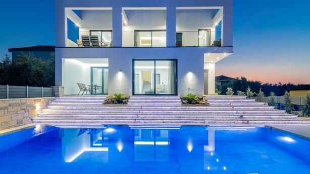 Una moderna casa a due piani con piscina di fronte.