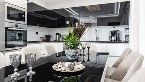 Una cucina moderna con un piano di lavoro nero, elettrodomestici in acciaio inossidabile e un'isola centrale con una pianta e oggetti decorativi.
