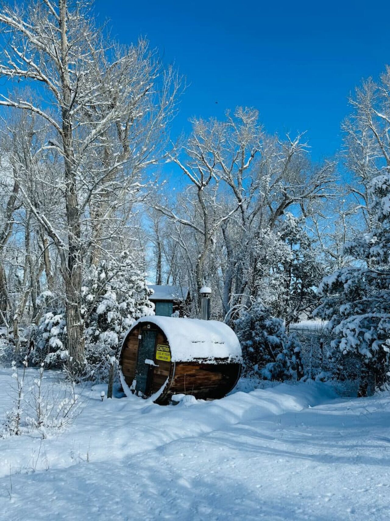 A snow-covered wooden barrel structure in a forest.