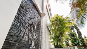 Ein moderner Außenduschebereich mit einer Steinwand und einem Wasserspiel.