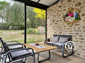 Un interior moderno con un amplio ventanal, pared de piedra, un sofá y una mesa de comedor.