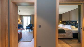 A hotel room with a bed, a desk, and a chair. There is a view of the hallway and another room.