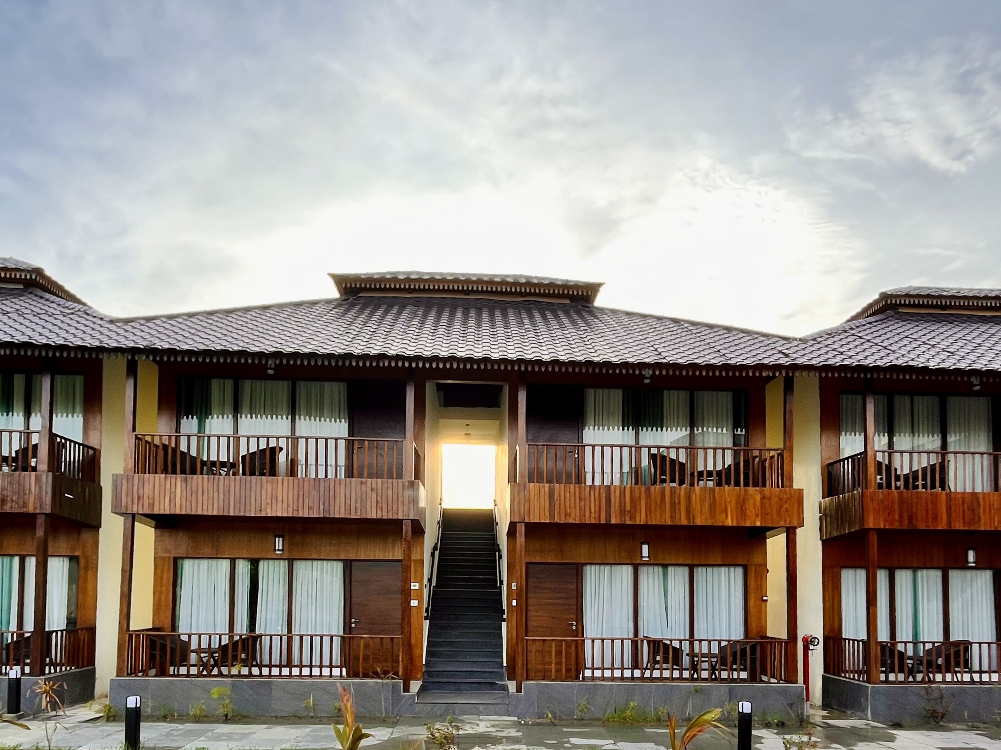 A traditional-style building with multiple balconies, large windows, and a central staircase leading to the entrance.