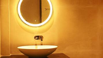 Un baño con un espejo redondo, un lavabo y un grifo.