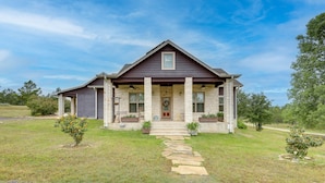 A two-story house with a stone facade, a front porch with columns, and a pathway leading to the entrance. - Pool & Hot Tub in Sunny Smithville Getaway! (Smithville)