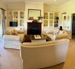 A living room with two sofas, a coffee table, a fireplace, and a bookshelf.