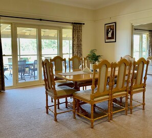 A dining area with a wooden table and chairs, a potted plant, and a framed picture on the wall.