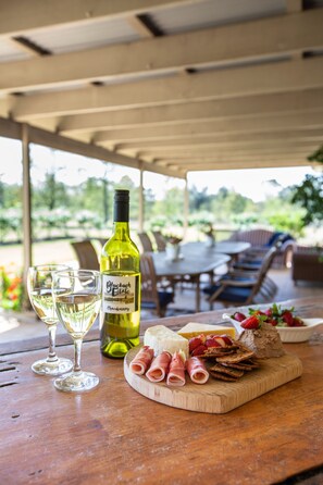 A wooden table with a bottle of wine, glasses, cheese, and cured meats.