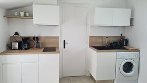 A compact kitchen with white cabinets, a built-in washing machine, and a coffee maker.