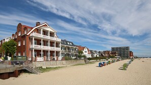 Um hotel na praia com várias varandas, uma praia de areia e céu claro.