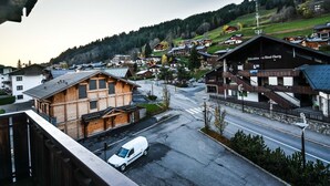 Eine Stadt mit Holzhäusern, einem weißen Lieferwagen und einer Straße, die zu einem Hügel führt.