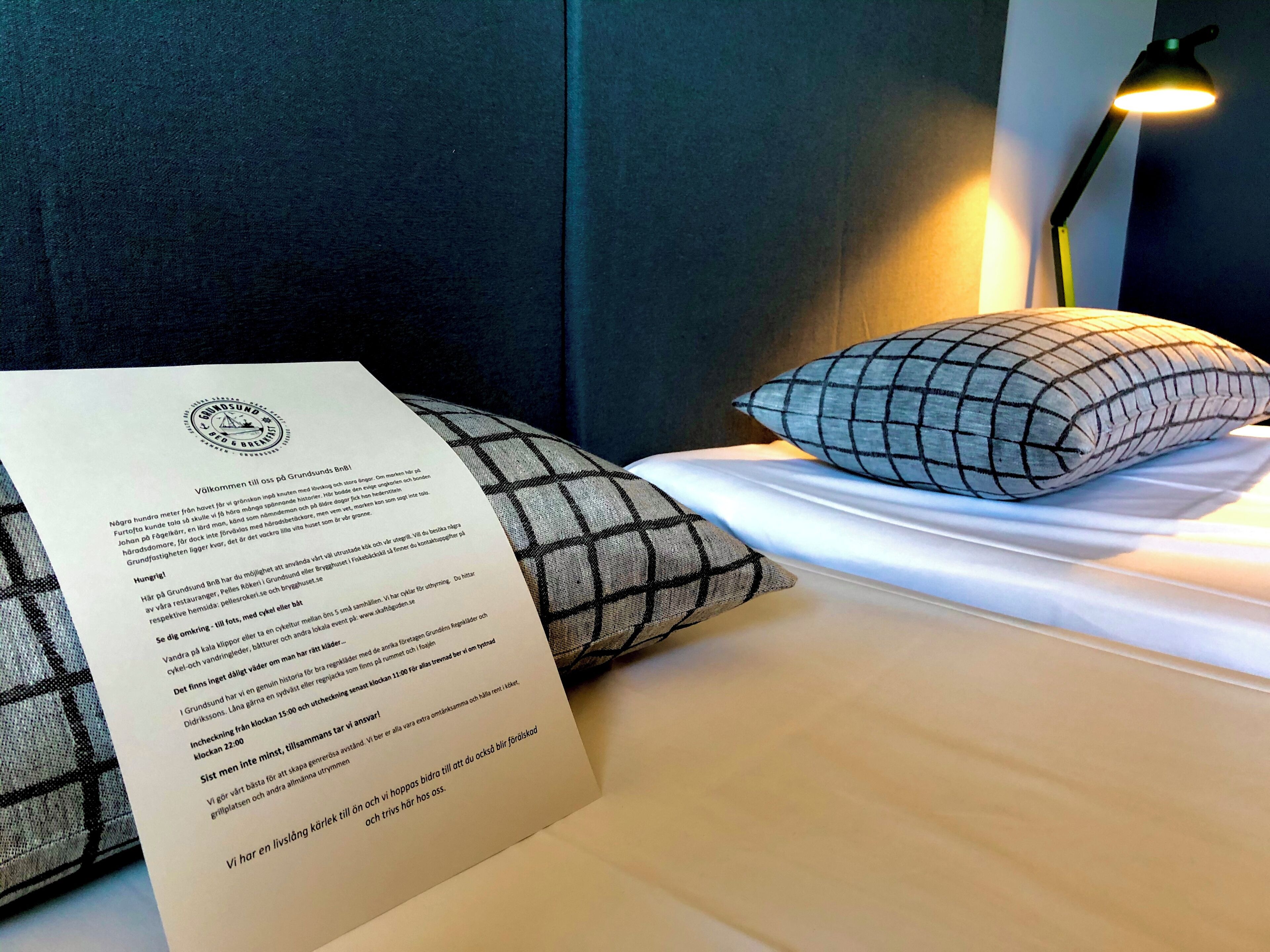 Une chambre d’hôtel avec un lit, des oreillers, une table de chevet et une lampe.