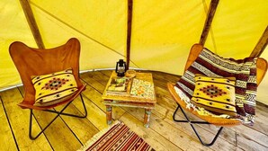A tent interior with two chairs, a small table, and a lantern.