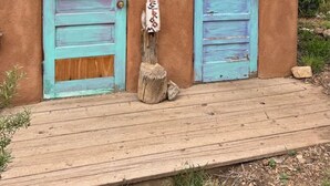 A rustic cabin with two doors labeled 'SHOWER' and 'TOILET' and a wooden deck in front.