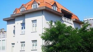 Ein mehrstöckiges Gebäude mit roten Ziegeldach, weißen Außenwänden und einem Balkon.