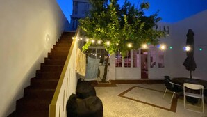 A staircase leading to a covered outdoor area with a tree, string lights, and a seating area with chairs. - Charming 5-bed House in Granja (Mourão)