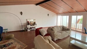 A spacious living room with a high ceiling, a sofa, a coffee table, and a decorative cabinet. - Charming 5-bed House in Granja (Mourão)