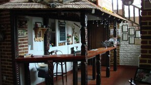 A rustic bar area with exposed brick walls, wooden beams, and a high ceiling. - Pensiunea Padina Ursului (Fundata)