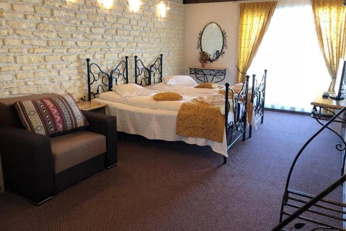 A room with a bed, a sofa, a mirror, and a stone wall.