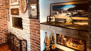 A room with a stone wall, framed certificates, and a fireplace with historical paintings. - Pensiunea Padina Ursului (Fundata)