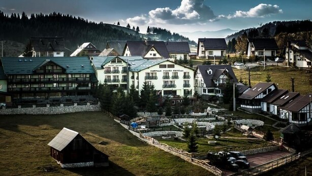 A hotel with multiple buildings, a swimming pool, and a mountainous backdrop. - Pensiunea Padina Ursului (Fundata)