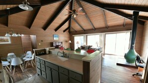 A spacious kitchen with a large island, wooden beams, and a dining area with chairs and a table. - Spacious, renovated 3 bedroom home in Traverse City (Traverse City)