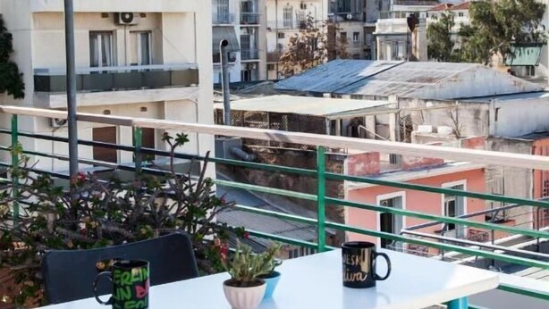 Une terrasse avec une table blanche, deux chaises et deux plantes en pot.