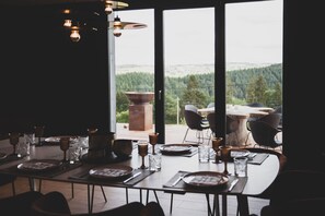 A dining area with a table set for four, overlooking a forested landscape.