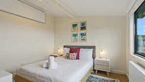 A neatly arranged bedroom with a bed, bedside tables, and wall art.