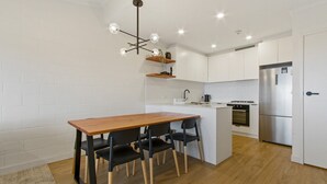 A modern kitchen with white cabinets, a wooden dining table, and black chairs.