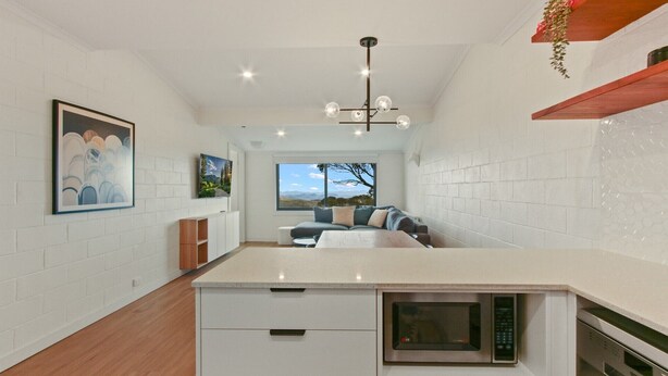 A modern kitchen with a central island, built-in microwave, and a large window offering a view of the outdoors.