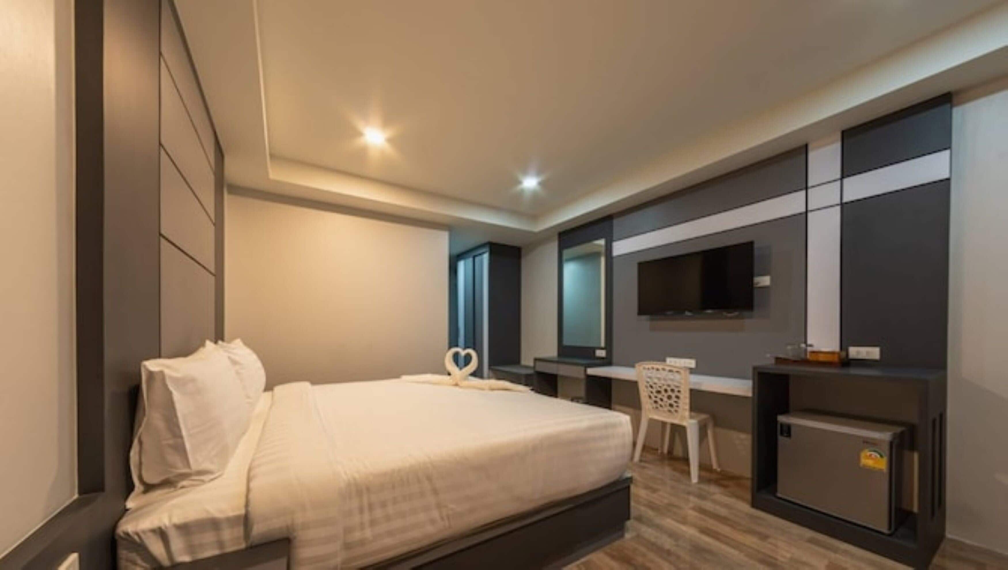 Una habitación de hotel moderna con una cama grande, un escritorio, un televisor y un minibar.